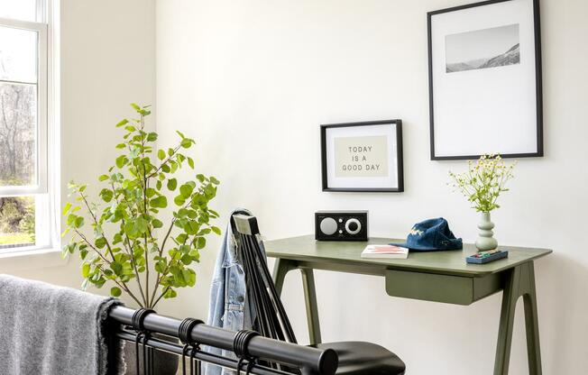 a green desk with a black chair in a bedroom