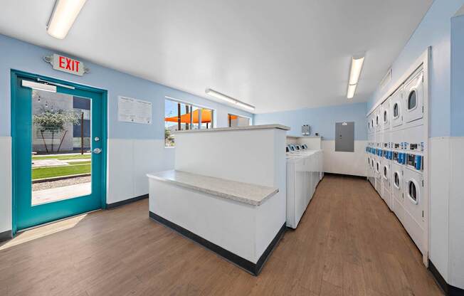 A laundromat with a blue door and a washer and dryer.