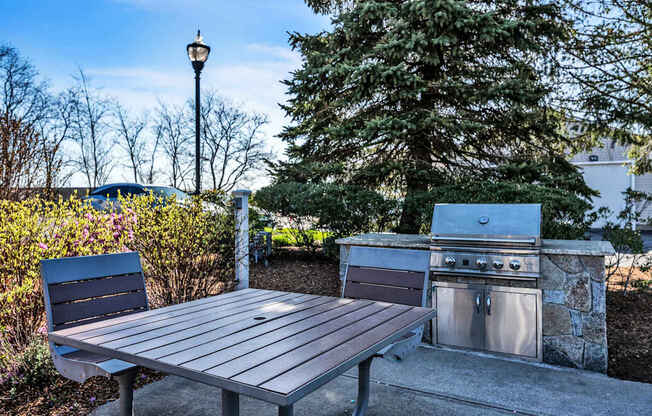 A picnic table is in front of a grill at the Ledges Apartments.