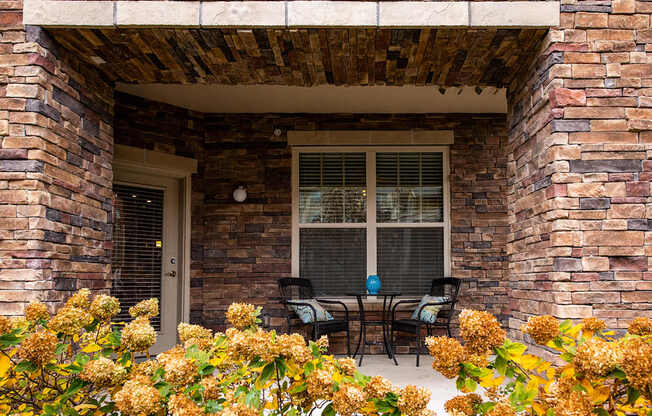 A patio with a table and chairs is framed by a brick wall.