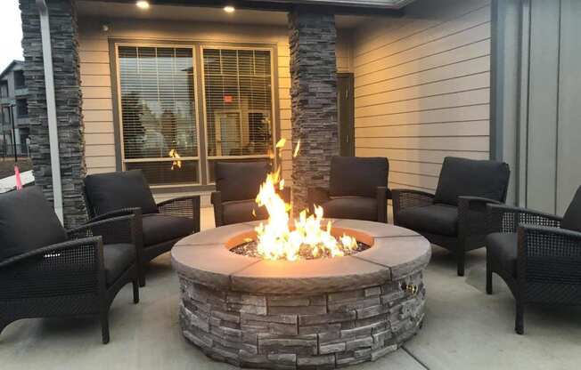 a fire pit on the patio of a home with chairs