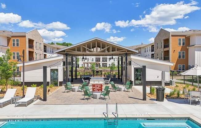 A swimming pool is surrounded by sun loungers and a pavilion.