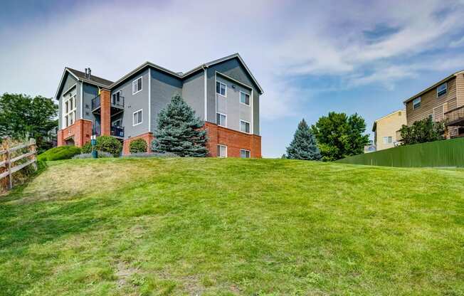 the backyard of a house on a hill with green grass