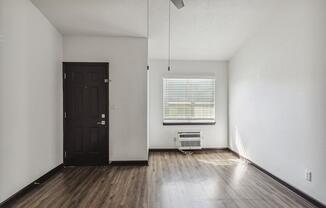 an empty living room with wood floors and a black door