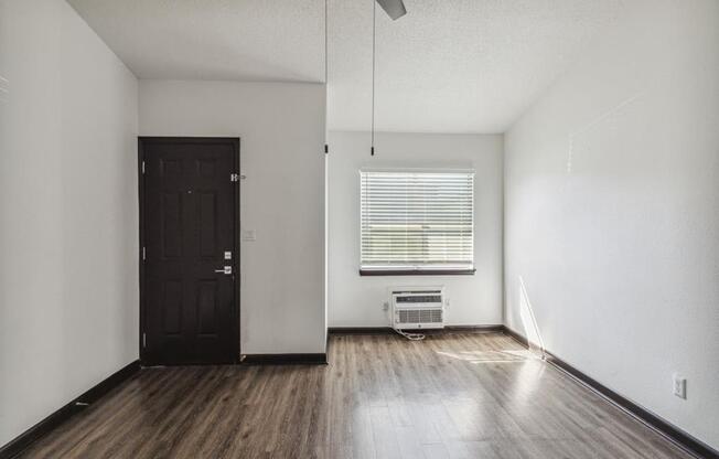 an empty living room with wood floors and a black door