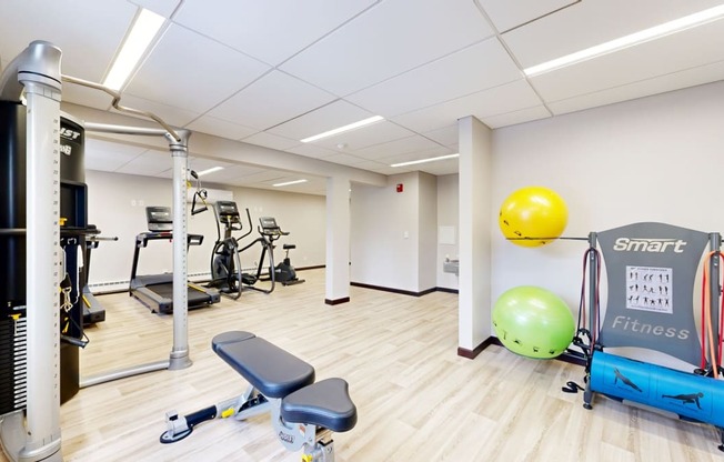 a gym with exercise equipment and a yellow ball on the wall