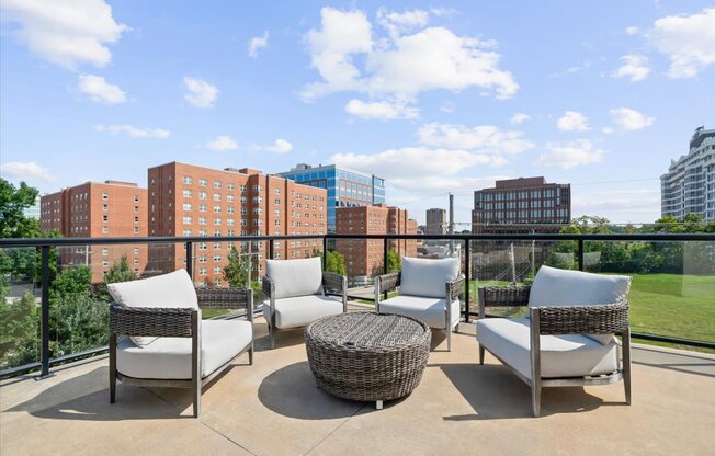 A patio with four chairs and a table with a view of a city skyline.