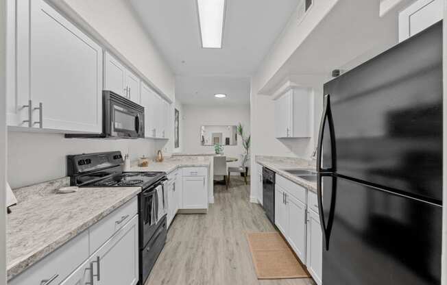 a kitchen with white cabinets and black appliances