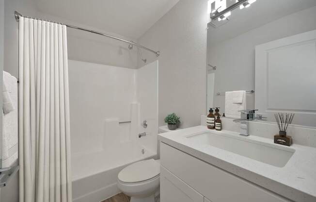 A white bathroom with a toilet, sink, and shower.