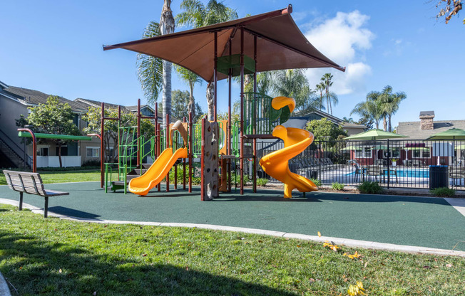 a playground with two slides and an umbrella in a park