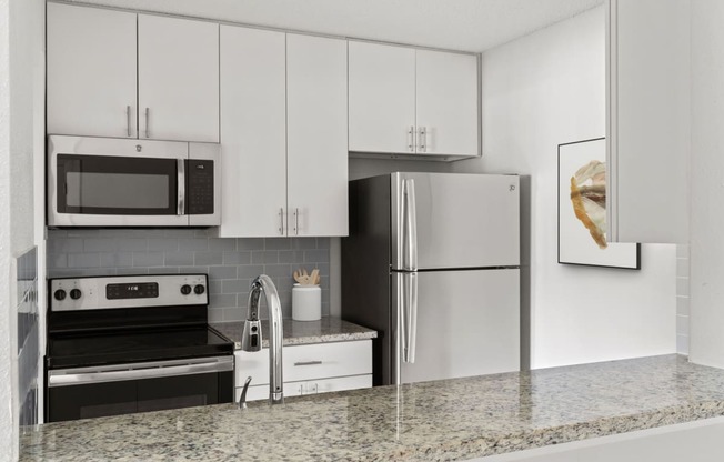 a kitchen with white cabinets and a stainless steel refrigerator