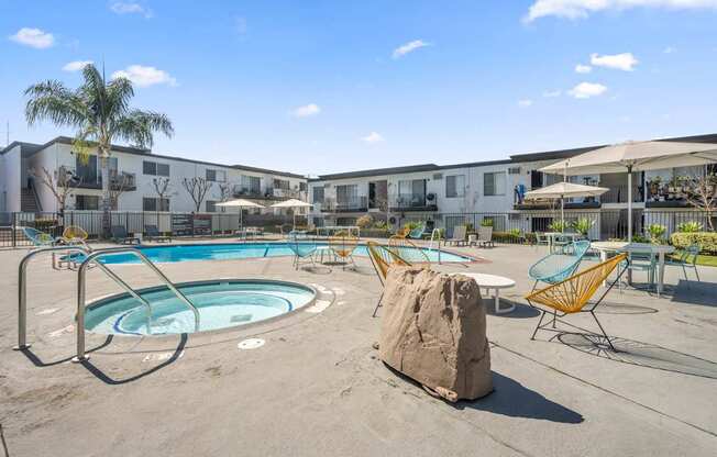 A swimming pool surrounded by chairs and a rock.
