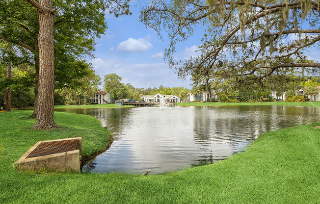 Lake with a fountain and apartment building in the background at Vue at Baymeadows Apartments in Jacksonville, Florida