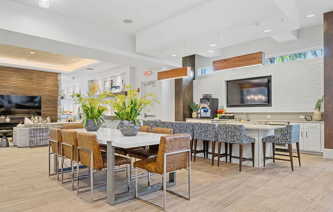 a dining area with a table and chairs and a kitchen with a television