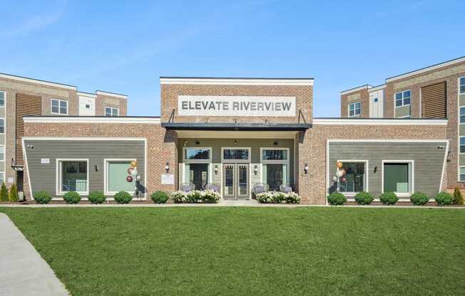 The front of a building named Elevate Riverview with a green lawn in front.