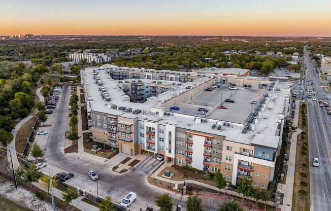 A large apartment complex is surrounded by a parking lot and a road.