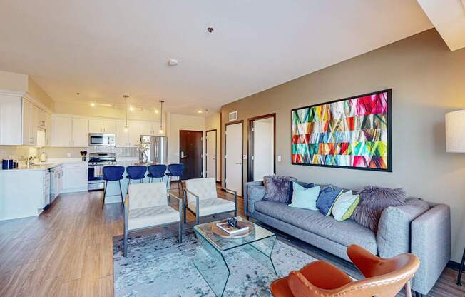 A modern living room with a grey couch and a painting on the wall.