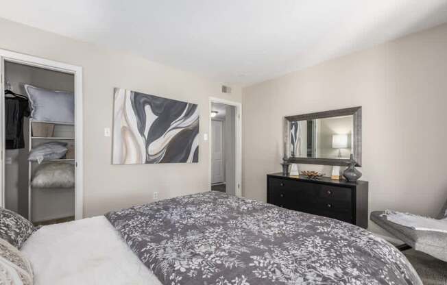 A bedroom with a large bed and a dresser with a mirror.