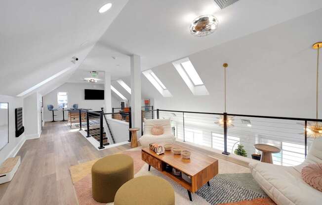 A modern living room with a white sofa, a wooden coffee table, and a balcony with a railing.