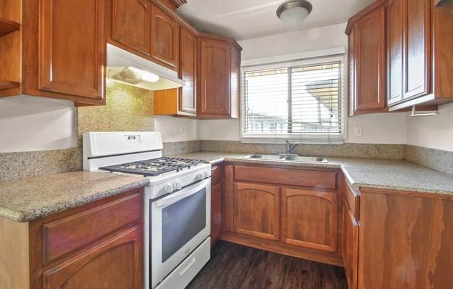 Kitchen with white gas stove, granite countertops, wood style kitchen cabinets