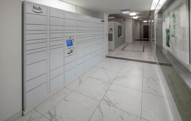 a photo of a long white hallway with white marble floors and white lockers with a blue at The Parker, Portland