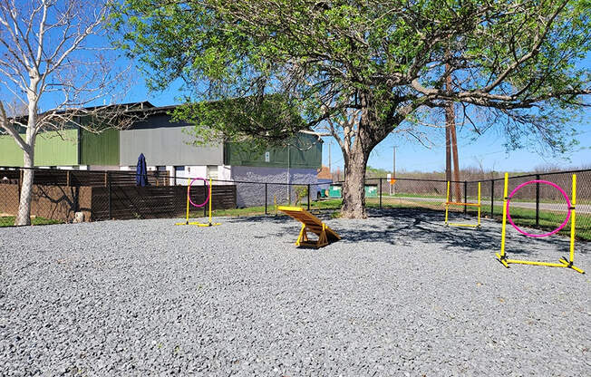 a playground with swings and a tree in front of a building at Ivy Plains at Brooks Apartments, San Antonio , TX, 78223