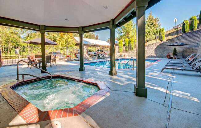 A hot tub is surrounded by a pool and a patio area.