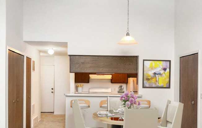 a dining area with a table and chairs and a kitchen in the background