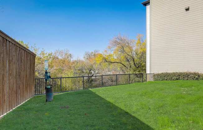 A backyard with a wooden fence and a green lawn at Infinity on the Point Apartments, Texas