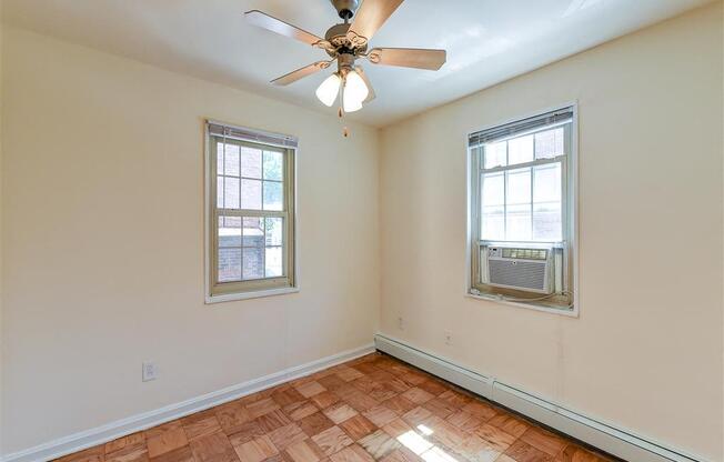 vacant bedroom with hardwood flooring and ceiling fan at alpha house apartments in washington dc