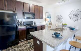A kitchen with a black refrigerator and a granite countertop.