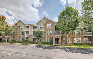 A large apartment complex with a parking lot in front.
