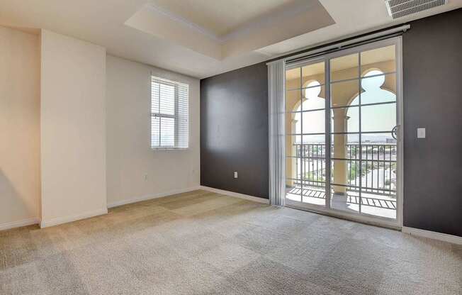 A room with a carpeted floor and a sliding glass door leading to a balcony.