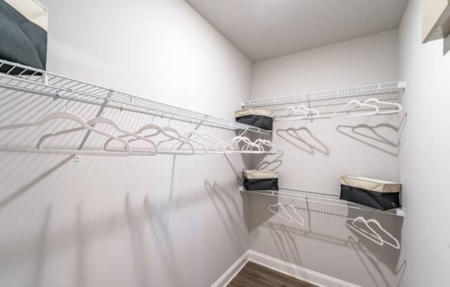 spacious closet with white walls and shelves with white mirrored closets with wire hanging racks