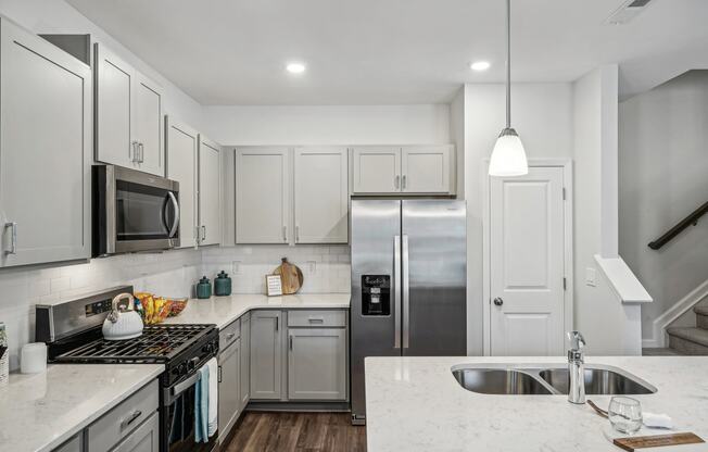 a white kitchen with stainless steel appliances and marble counter tops