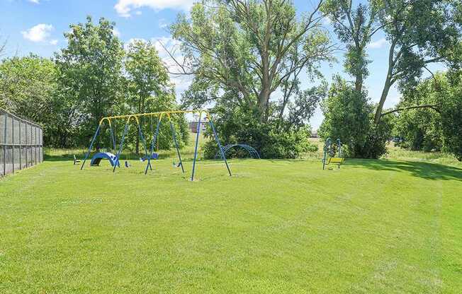 A playground with a yellow swing set in a grassy area.