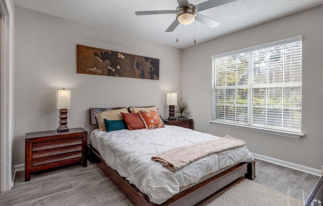 A bedroom with a bed, nightstand, and a painting on the wall.
