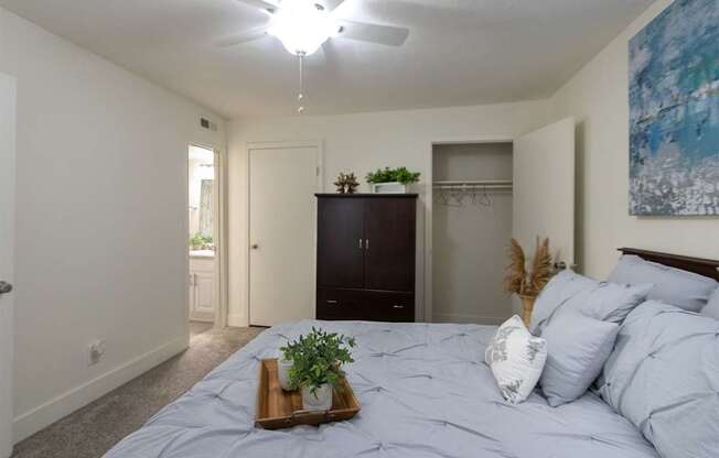 A bedroom with a bed, white ceiling fan, and a painting on the wall in a 1 bedroom, 1 bath 554 sq ft apartment home at The Biltmore Apartments located in the Vickery Midtown neighborhood of Dallas, TX.