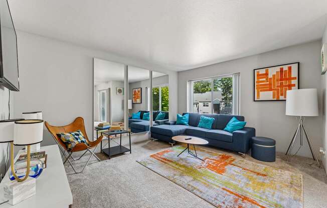 A living room with a blue couch and a colorful rug.