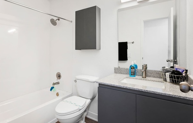 A white toilet with a blue toy on the seat sits in a bathroom.