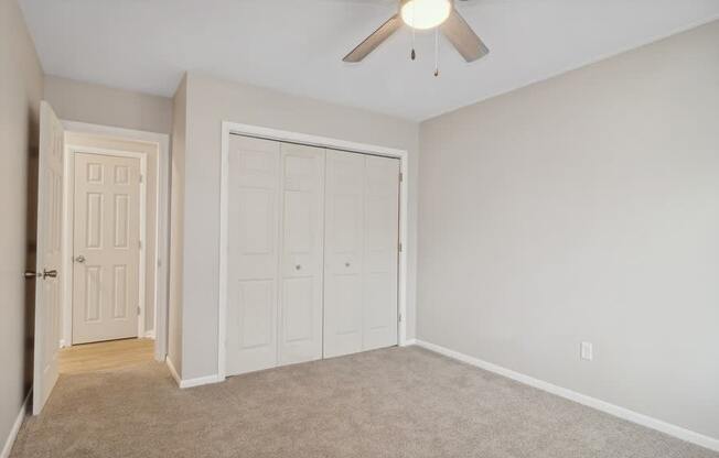 A room with a ceiling fan and two doors.