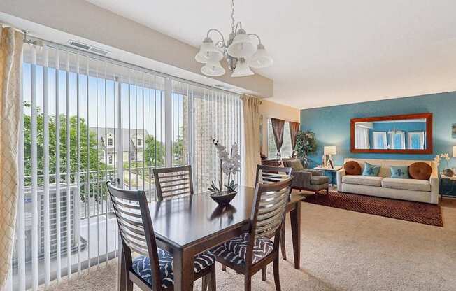 A dining room with a table and chairs and a view of the outside.