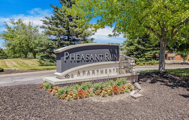 an entrance sign for the Pheasant Run Apartments on the side of a road