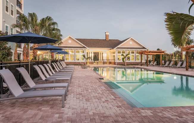 a pool with lounge chairs and a house in the background