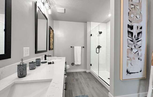 Main bathroom in model with dual vanities and frameless walk-in shower