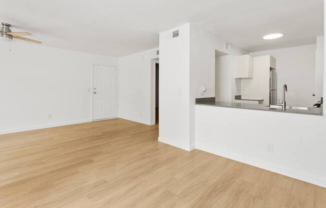 A room with a kitchen area and a wooden floor.