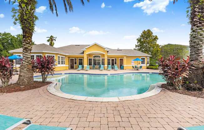 A yellow house with a pool in the backyard.