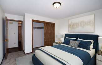 a bedroom with a bed and a closet and a door to a bathroom.  Fargo, ND Country Club Apartments