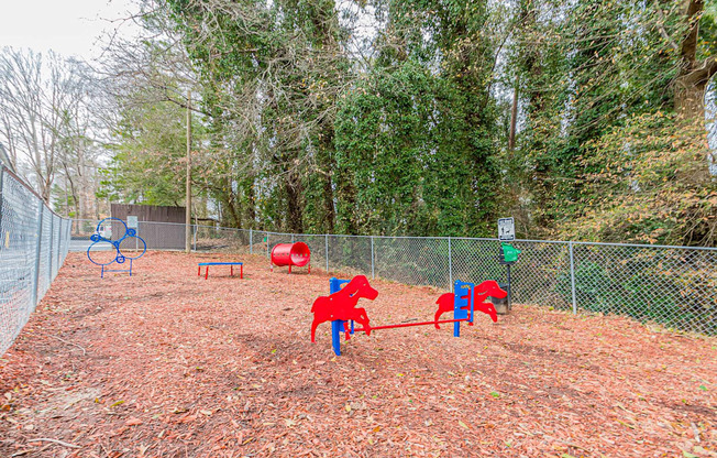A playground with red and blue equipment surrounded by a fence.