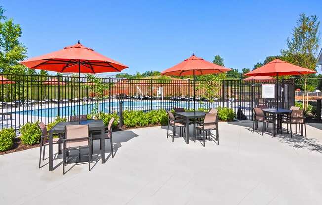 a patio with tables and umbrellas next to a pool